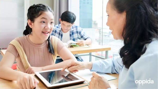 2 Teacher helping student with tablet in class